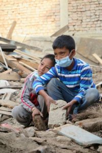 Two brothers help their dad & uncles pick up whole bricks that come from collapsed buildings. 